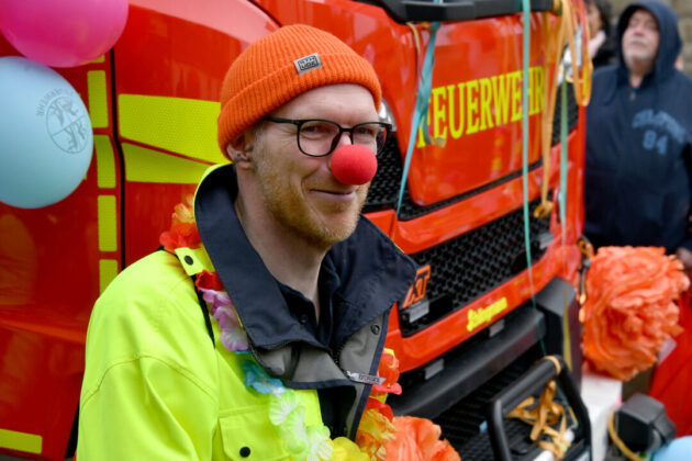 Feuerwehrmann mit roter Nase lächelt bei Veranstaltung.