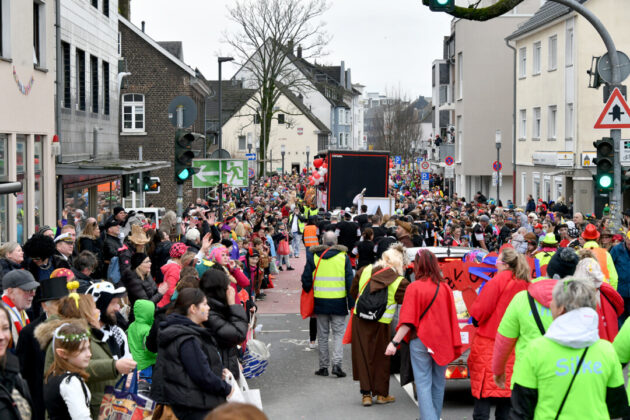 Karnevalsumzug mit Menschenmengen auf Straße.