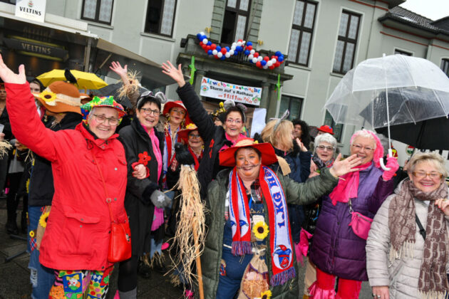 Fröhliche Menschen bei Karnevalsfeier draußen.