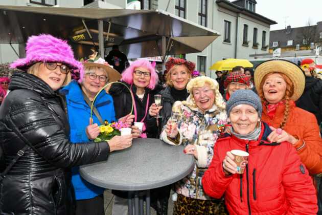 Gruppe fröhlicher Frauen feiert Karneval im Freien.