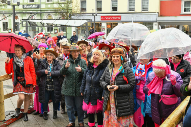 Leute feiern Straßenkarneval trotz Regen.