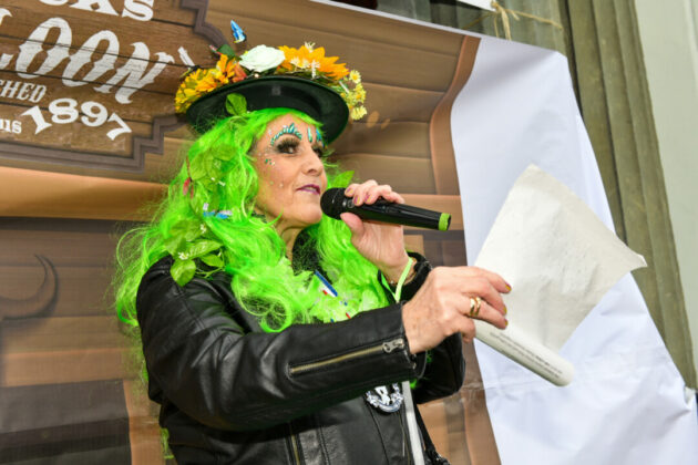 Frau mit grünen Haaren singt bei Veranstaltung.