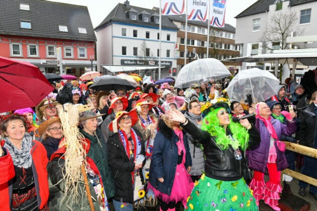 Karnevalsumzug mit kostümierten Menschen und Regenschirmen.