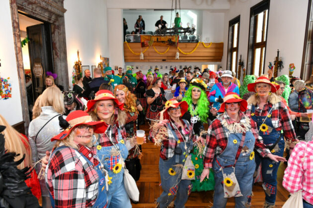 Karnevalsparty mit kostümierten Gästen in einem Saal.