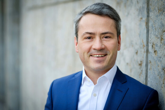 Lächelnder Mann im Anzug vor Betonwand