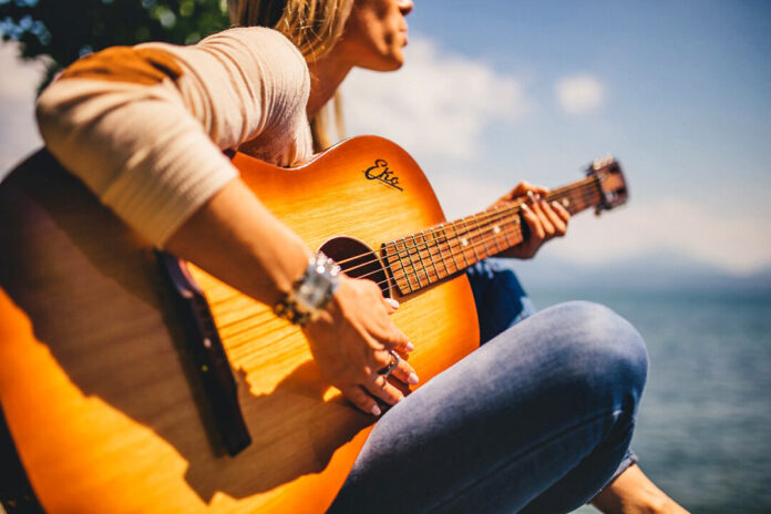 Person spielt Gitarre am Seeufer