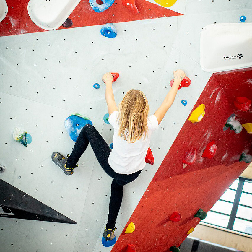 Person klettert an bunter Indoor-Kletterwand.