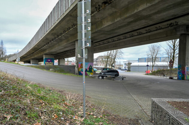 Betonbrücke mit Graffiti, Auto und Straßenlaterne.