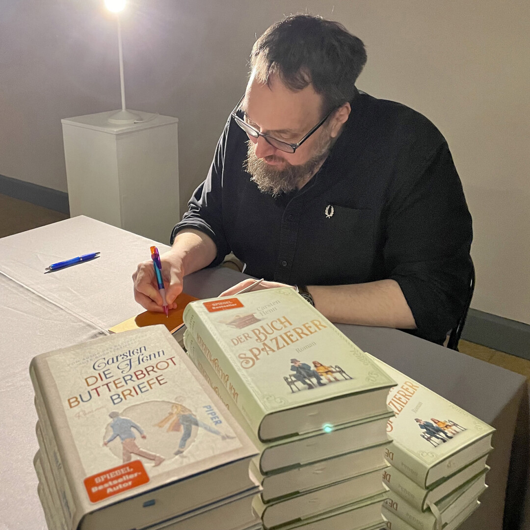 Autor signiert Bücher bei Veranstaltung.