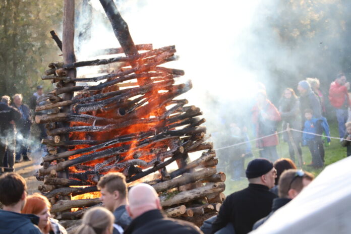 Traditionelles Lagerfeuer mit Zuschauern im Freien.