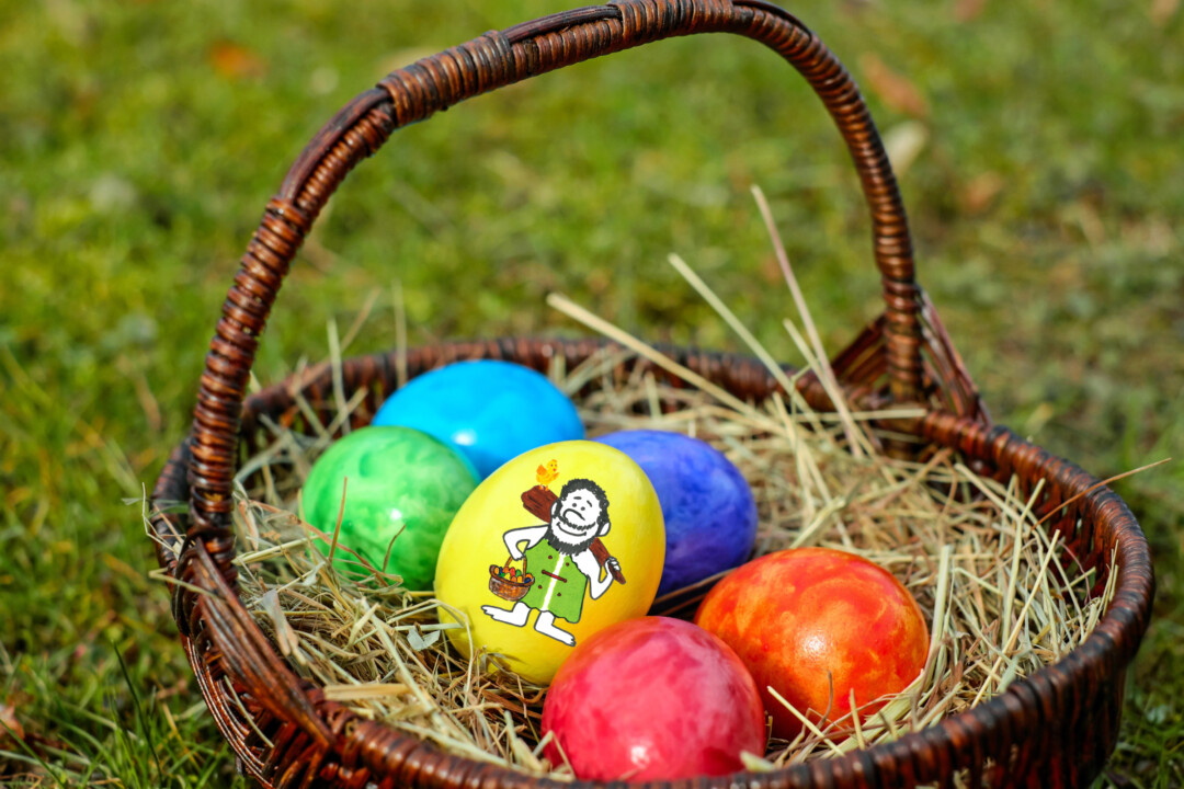 Bunter Osterkorb mit bemalten Eiern auf Gras