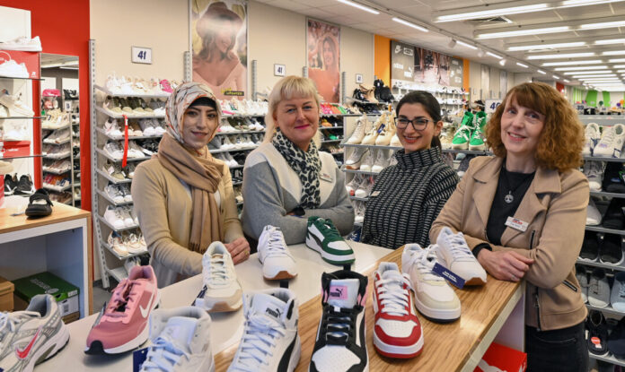 Frauen präsentieren Schuhe im Geschäft.