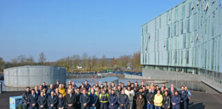 Gruppenfoto von Mitarbeitern vor modernem Bürogebäude.