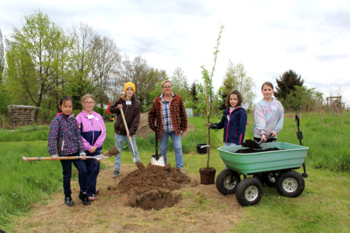 Unter Anleitung von Karin Blomenkamp (4.v.l.), Leiterin des Naturschutzzentrums, hat der Arbeitskreis Umwelt des Erkrather Kinderparlaments einen Obstbaum im Naturschutzzentrum Bruchhausen gepflanzt. Foto: Stadt Erkrath