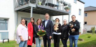 Bürgermeister Christoph Schultz (4.v.l.) besuchte anlässlich des dreijährigen Bestehens die Intensivpflege-Wohngemeinschaft „aidura“ in Hochdahl und überbrachte WG-Koordinatorin Ines Aust (3.v.l.) einen Strauß Blumen. Foto: Stadt Erkrath