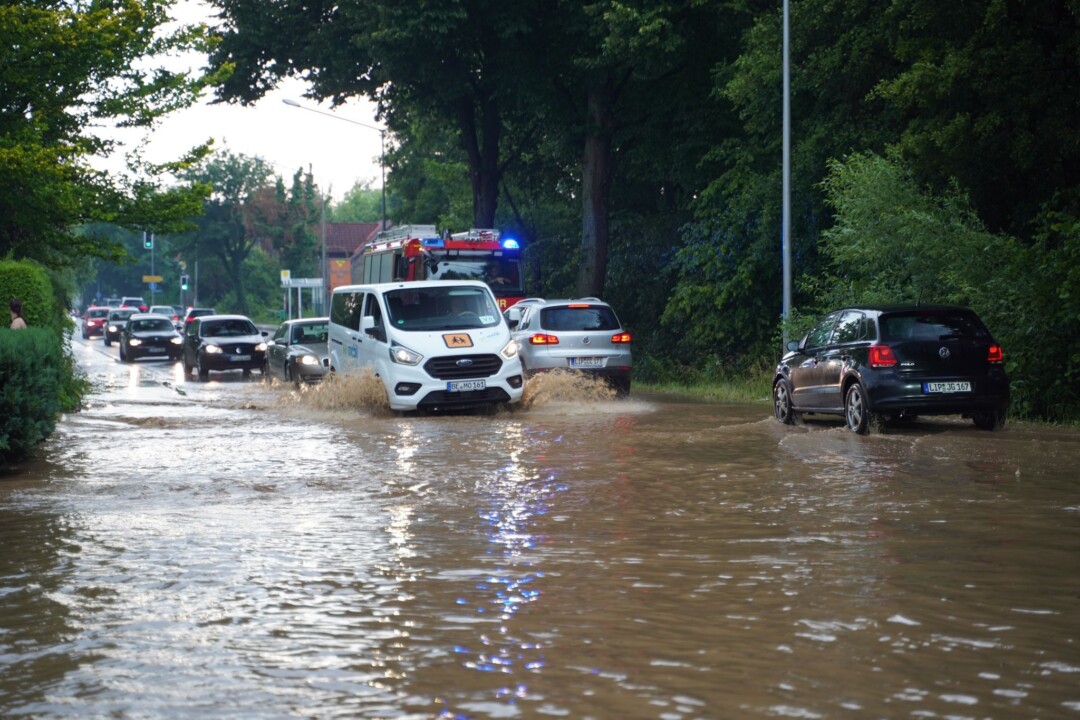 Autos fahren nach einem Unwetter durch Wasser, das auf einer überfluteten Straße steht. Bei einem heftigem Unwetter in Detmold im Kreis Lippe sind nach Stadtangaben binnen kurzem bis zu 100 Liter Regen pro Quadratmeter gefallen.