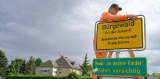 Der Ort Morschenich-Alt heißt fortan «Bürgewald». Ein Mitarbeiter von Straßen.NRW bringt das neue Schild an.