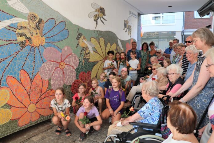 Viele junge und ältere Künstler nahmen an der Enthüllung ihres gemeinsamen Mosaik-Werks zwischen Bechemer Straße und Am Alten Steinhaus teil. Mit ihnen freuen sich die Eigentümer Achim und Manuela Egenberger sowie die Chef-Künstlerin Sarah Rose (im Hintergrund v.l.). Foto: Stadt Ratingen
