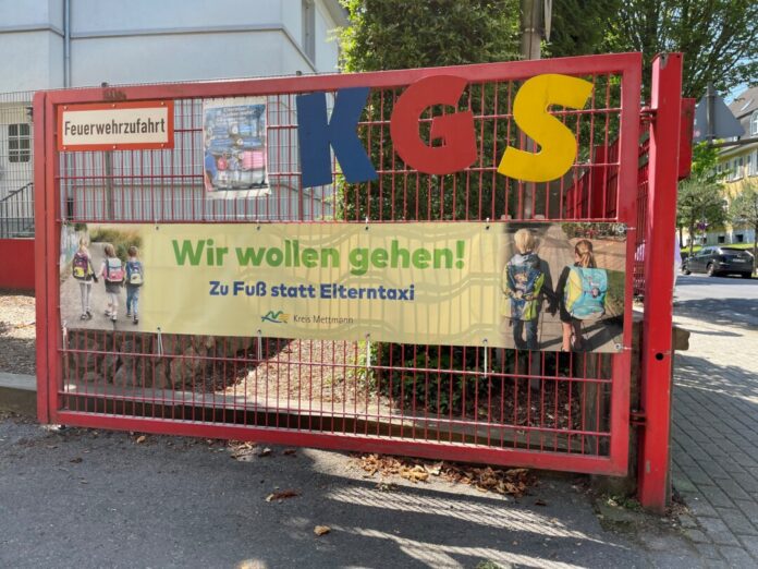 Am Eingangstor der Katholischen Grundschule hängt ein großes Banner: "Wir wollen gehen! Zu Fuß statt Elterntaxi". Foto: Kreisstadt Mettmann