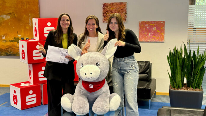 Weltsparwoche Adriane Schröder, Christina Biedebach und Sabrina Vößing von der Kreissparkasse Düsseldorf präsentieren den Hauptpreis des Mal- und Geschichtenwettbewerbs. Foto: Sparkasse