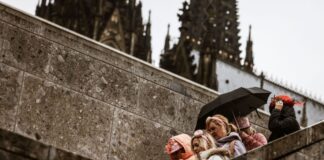 Karnevalistinnen feiern im Februar 2024 mit Regenschutz am Kölner Dom. (Archivbild)