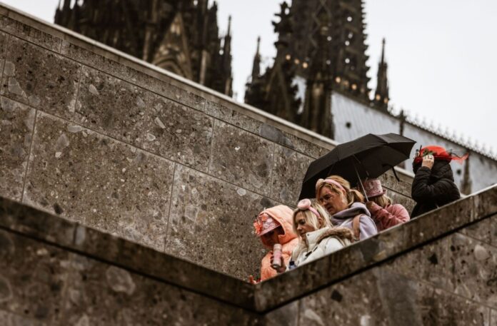 Karnevalistinnen feiern im Februar 2024 mit Regenschutz am Kölner Dom. (Archivbild)