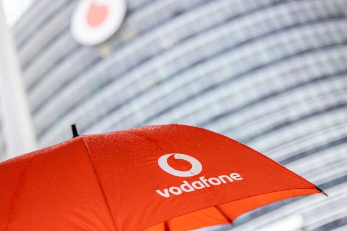 Ein Passant geht mit einem aufgespanntem Regenschirm mit dem Logo von Vodafone an der Zentrale der Deutschlandtochter des britischen Vodafone-Konzerns vorbei.