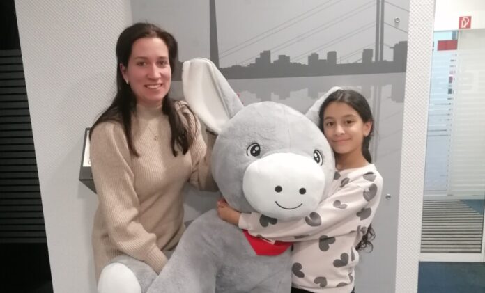 Jasmin hat den Malwettbewerb der Kreissparkasse gewonnen und erhält den XXL-Esel Olli von Christina Biedebach (Kreissparkasse Düsseldorf). Foto: Sparkasse