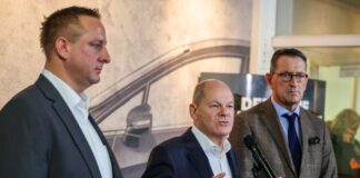 Betriebsratschef Benjamin Gruschka (l) neben Bundeskanzler Olaf Scholz (SPD) und Marcus Wassenberg (r), Geschäftsführer der Ford-Werke.