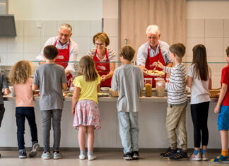 Die Ehrenamtler bereiten das Frühstück vor und helfen den Kindern bei der Auswahl. Foto: Brot-Zeit/Barbara Gandenheimer