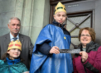 Leonhard und Jarmo (l.) brachten mit Hilfe von Sternsinger-Projektleiterin Alexandra Kneip und Bürgermeister Michael Beck den Segen an der Rathaustür an. Foto: Mathias Kehren