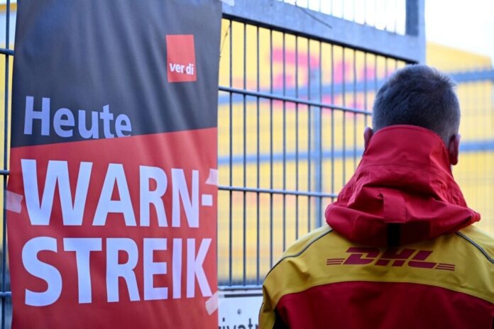 Streikposten am Werkstor: Ein DHL-Mitarbeiter hat die Arbeit niedergelegt und schaut auf eine Zustellbasis, in der er sonst arbeitet. 