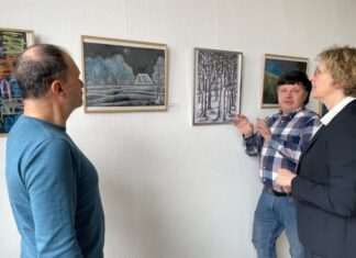 Bürgermeisterin Sandra Pietschmann, Michalis Papadopoulos (l.) und Orest Smishko, ein Freund der Künstler, schauen sich Bilder von Alexander Bondartschuk an. Foto: Kreisstadt Mettmann