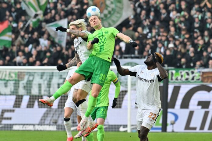 Wolfsburgs Patrick Wimmer (M) und Leverkusens Robert Andrich (l) im Kopfballduell. 