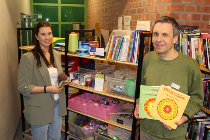 Abfallberaterin Nadine Conradi (l.) und Büchereimitarbeiter Juri Fischer (r.) sind Fans der Kreativ Regale in der Stadtbücherei Erkrath. Die interaktive Materialtauschbörse macht Lust aufs Basteln und ist zudem noch sehr nachhaltig. Foto: Stadt Erkrath