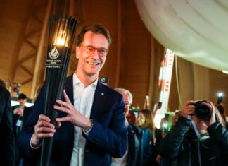Hendrik Wüst (CDU), Ministerpräsident des Landes Nordrhein-Westfalen, hält die Flamme der Welthochschulspiele. 