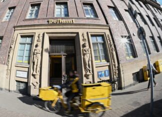 Eine Briefträgerin fährt an einer Postfiliale vorbei - vielleicht ist auch sie eine Beamtin?