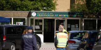 Polizisten stehen vor einer Schule im Berliner Bezirk Spandau, an der es am Vormittag einen möglichen Messerangriff auf einen Schüler gab.