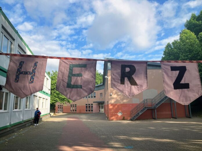Schüler einer Düsseldorfer Realschule haben eine Wimpelkette mit der Aufschrift "Herzlich Willkommen" selbst genäht und damit am Eingangstor 1.200 Erkrather Schüler begrüßt.  