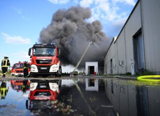 Feuerwehrleute löschen den Brand einer Lagerhalle mit Müll in Swisttal. 