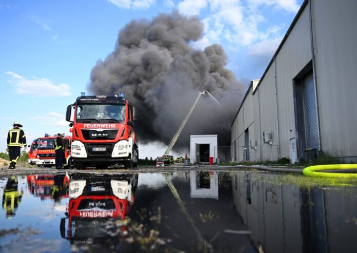 Feuerwehrleute löschen den Brand einer Lagerhalle mit Müll in Swisttal. 