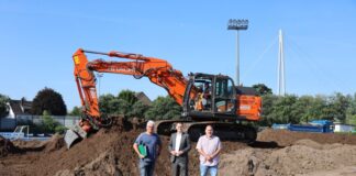 Dieser Erdhügel war mal der Stadionrasen, jedenfalls ein Teil davon, denn größtenteils war die Rasentragschicht bereits abtransportiert worden. Fachplaner Georg Schlate, Sportdezernent Patrick Anders und Projektleiter Achim Kramer (v.l.n.r.) erläuterten an Ort und Stelle die Baumaßnahme zur Erneuerung des Stadionrasens. Foto: Stadt Ratingen