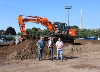 Dieser Erdhügel war mal der Stadionrasen, jedenfalls ein Teil davon, denn größtenteils war die Rasentragschicht bereits abtransportiert worden. Fachplaner Georg Schlate, Sportdezernent Patrick Anders und Projektleiter Achim Kramer (v.l.n.r.) erläuterten an Ort und Stelle die Baumaßnahme zur Erneuerung des Stadionrasens. Foto: Stadt Ratingen