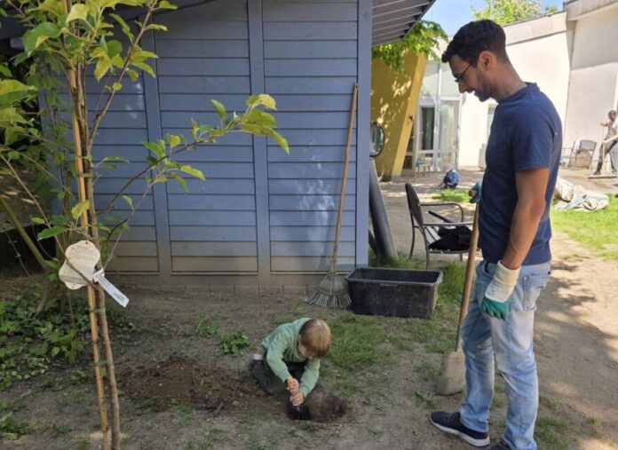 Ein Vater pflanzt mit seinem Kind einen Apfelbaum. Foto: Kreisstadt Mettmann