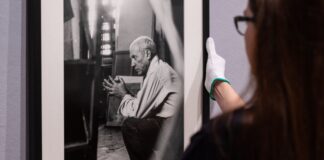 Eine Mitarbeiterin hängt ein eingerahmtes Foto von Pablo Picasso des Fotografen Herbert List an die Wand.