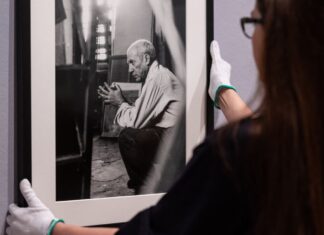 Eine Mitarbeiterin hängt ein eingerahmtes Foto von Pablo Picasso des Fotografen Herbert List an die Wand.