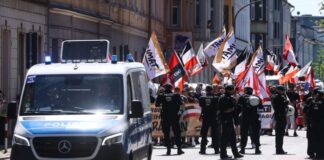 Mit Flaggen und Spruchbändern ziehen die Teilnehmer eines rechtsextremen Aufmarsches durch eine Stadt. Für einen Aufzug in Münster hat die Polizei Auflagen erteilt. (Archivbild)