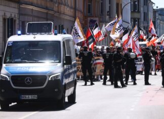 Mit Flaggen und Spruchbändern ziehen die Teilnehmer eines rechtsextremen Aufmarsches durch eine Stadt. Für einen Aufzug in Münster hat die Polizei Auflagen erteilt. (Archivbild)