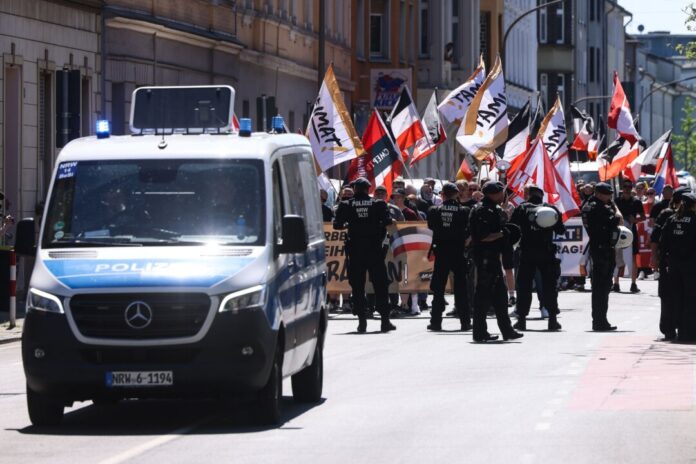 Mit Flaggen und Spruchbändern ziehen die Teilnehmer eines rechtsextremen Aufmarsches durch eine Stadt. Für einen Aufzug in Münster hat die Polizei Auflagen erteilt. (Archivbild)