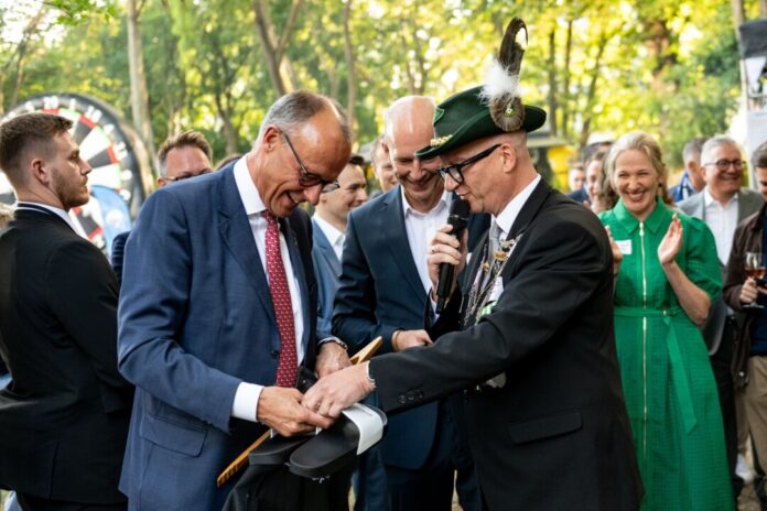 Bundeskanzler Friedrich Merz (CDU) bekommt beim Schützenfest der Sauerländer Botschaft Badeschlappen mit der Aufschrift «Rambo Zambo» geschenkt.